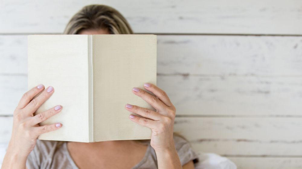Woman holding a book up in front of her face